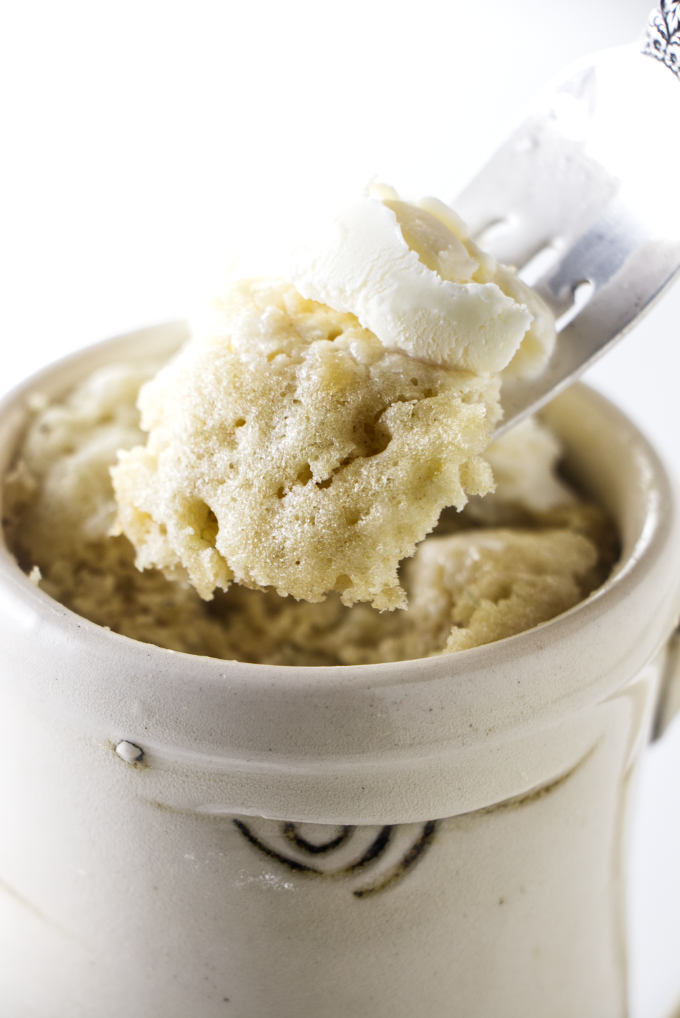 A fork holding a bite of banana cake in a mug.