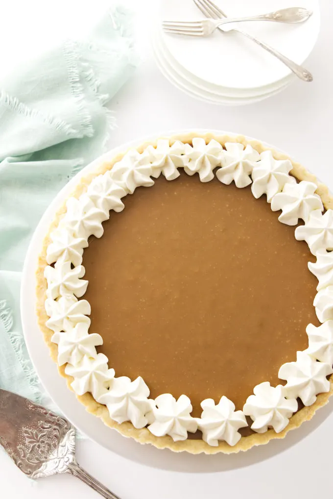 A whole butterscotch tart with whipped cream garnish.