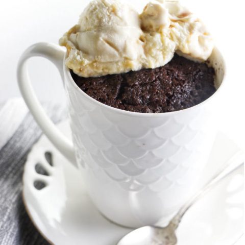 A coffee mug with a chocolate cake baked inside the mug.