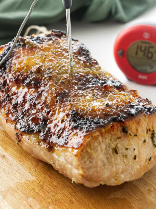 A pork roast with a garlic ginger glaze and a thermometer.