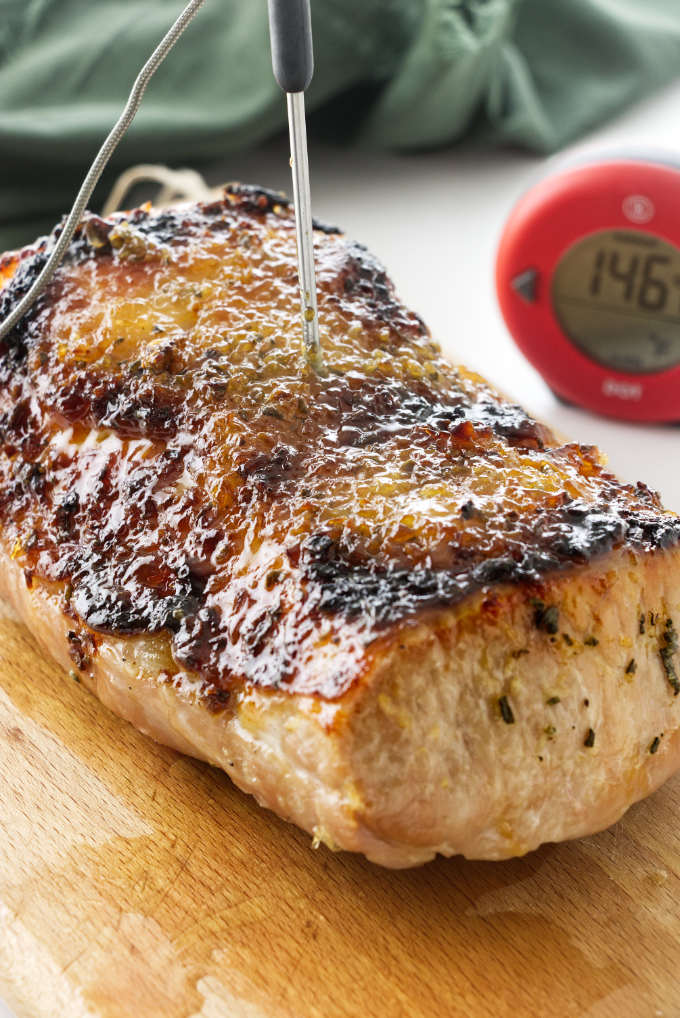 A pork roast with a garlic ginger glaze and a thermometer.
