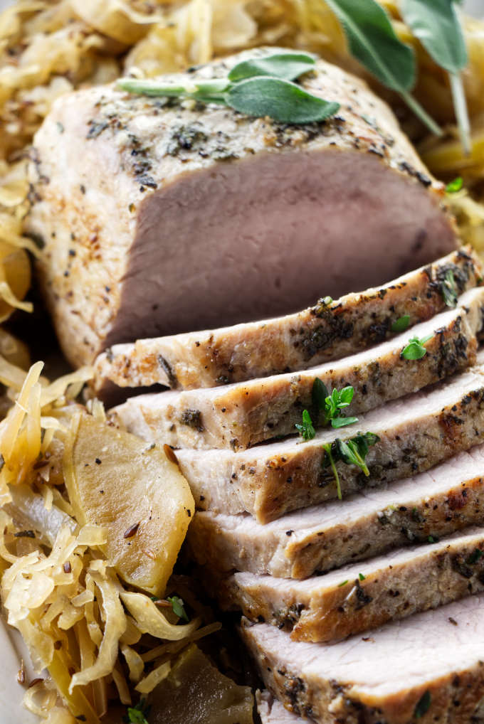 A pork roast on a platter with sauerkraut.