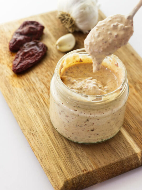 A spoon dipping into a jar of chipotle aioli.