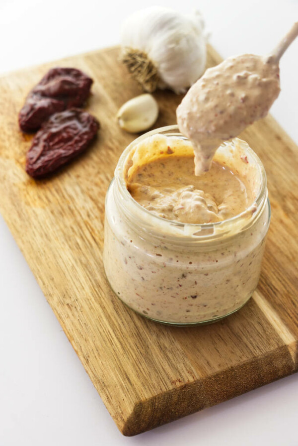 A spoon dipping into a jar of chipotle aioli.