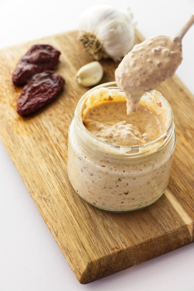 A spoon dipping into a jar of chipotle aioli.