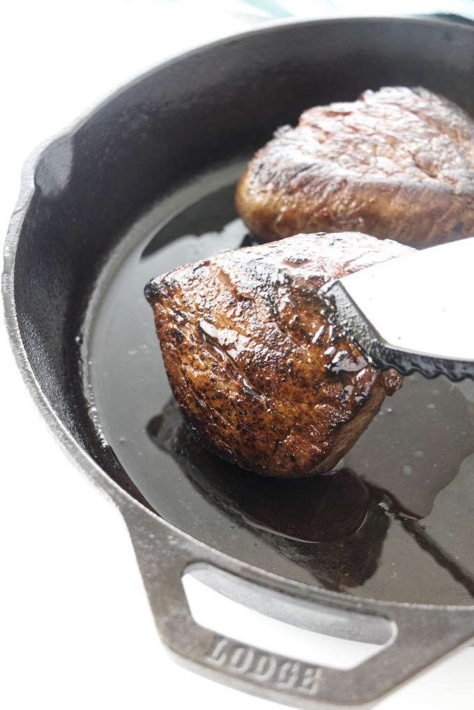 Tongs holding a Filet Mignon to sear the edges