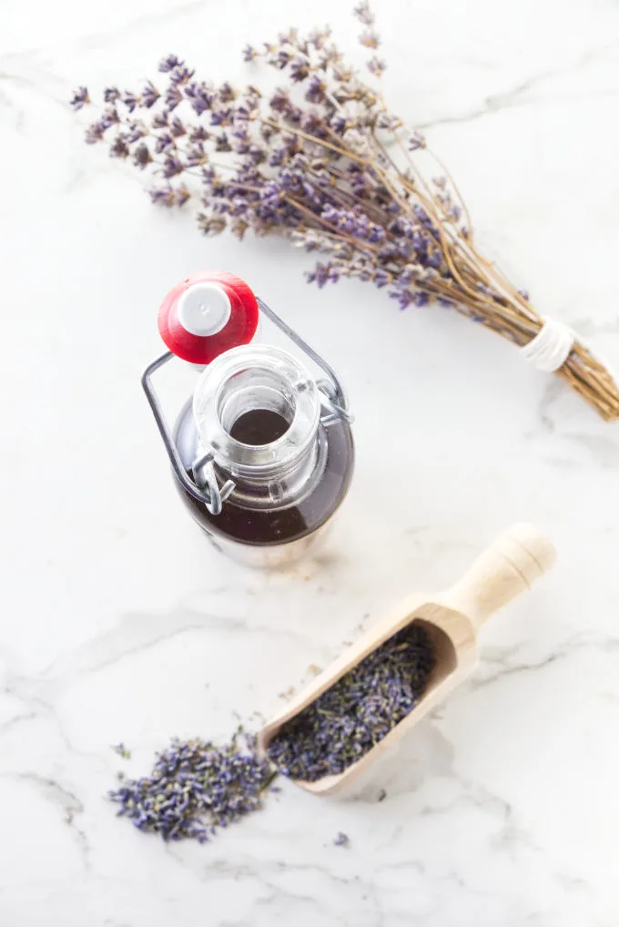 Culinary lavender buds and lavender syrup in a bottle.