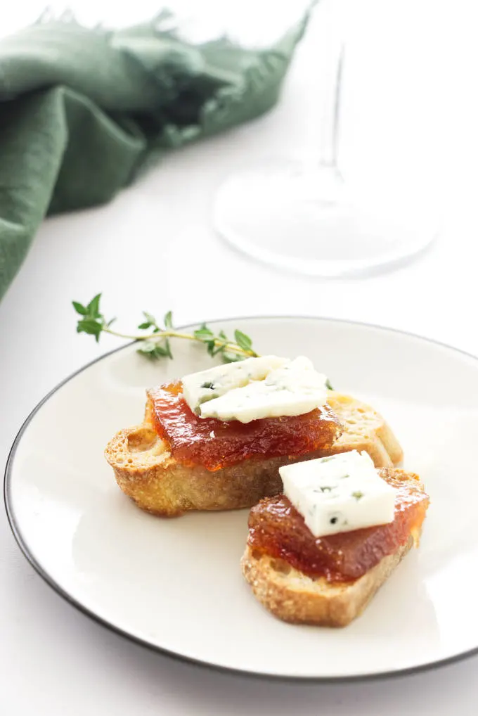 Crostini appetizers with pear paste and cheese on a small plate.