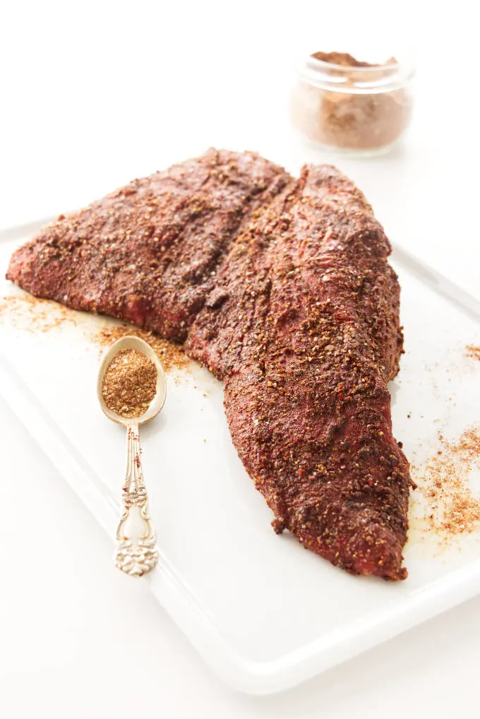 A tri tip steak covered in a spice rub.