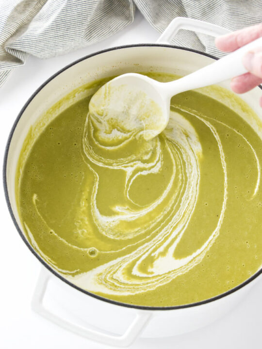 Adding cream to asparagus pea soup.