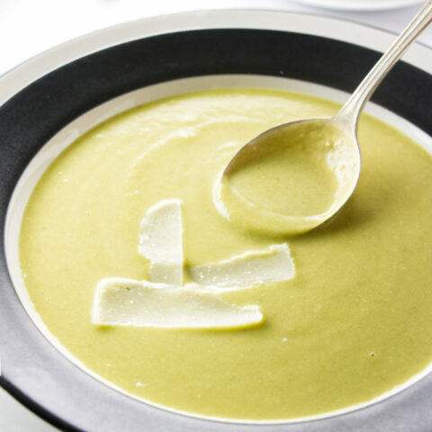 A bowl of asparagus pea soup with parmesan cheese.