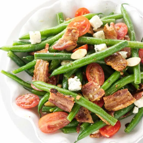 A dish of green bean salad with bacon and tomatoes.