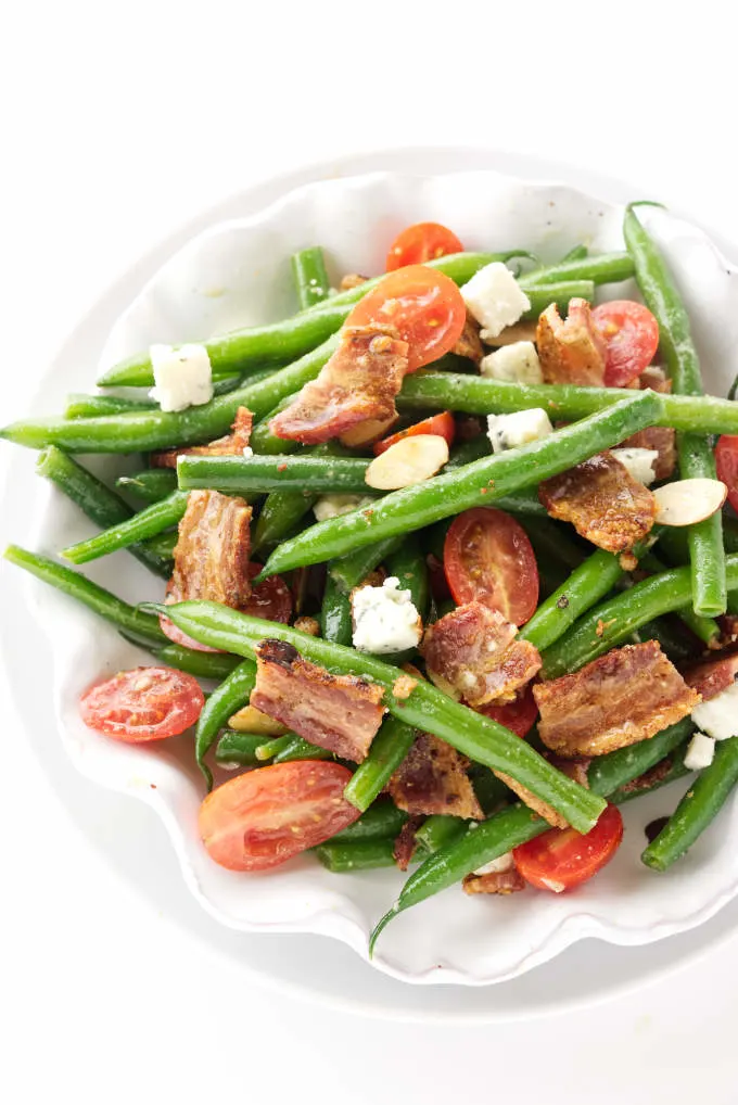 A dish of green bean salad with bacon and tomatoes.