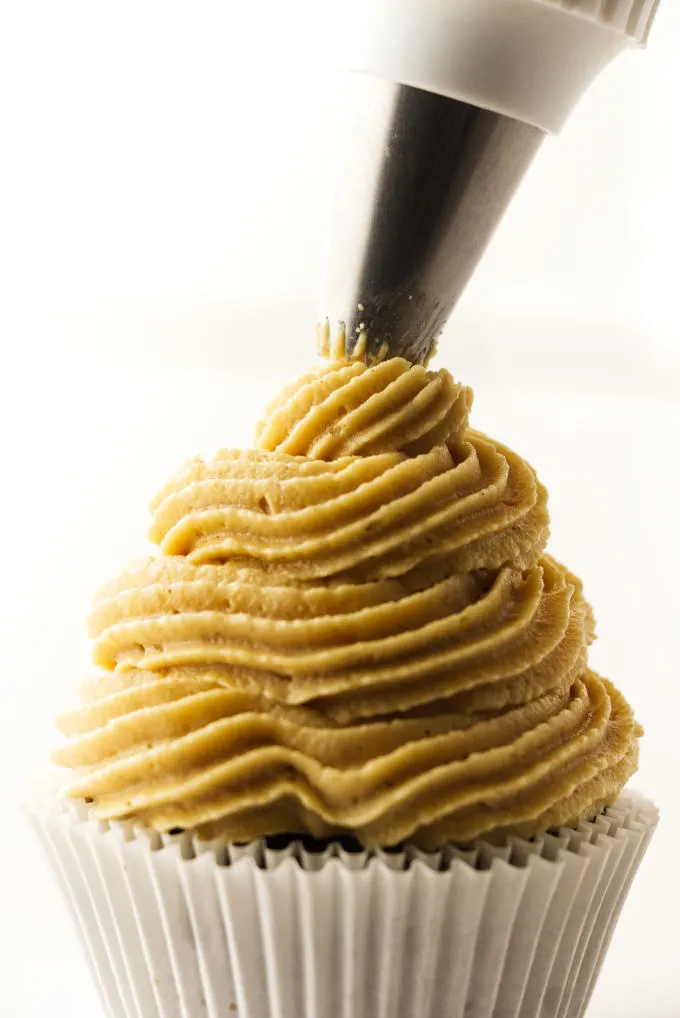 Peanut butter cream cheese frosting being piped on a cupcake.