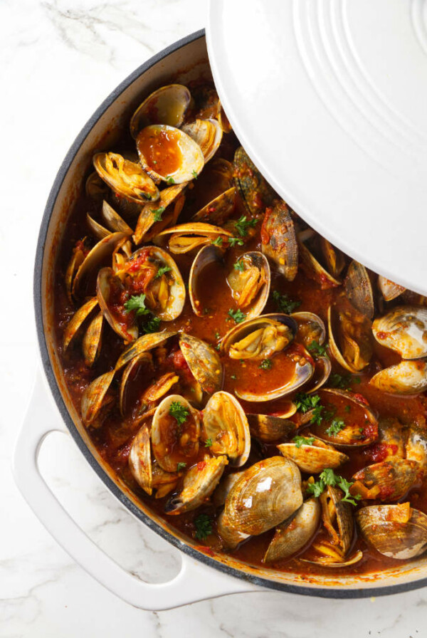 A large pot of clams in red sauce.