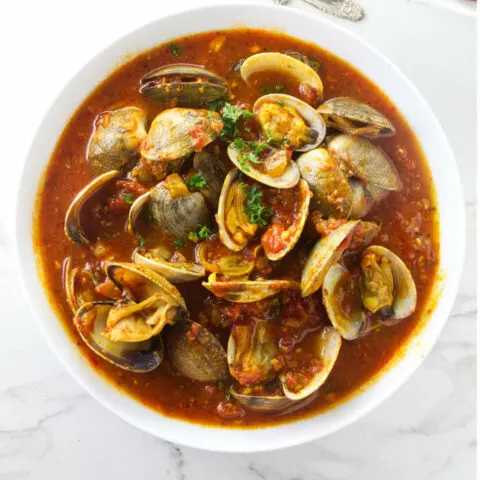 A large bowl of clams in red sauce.
