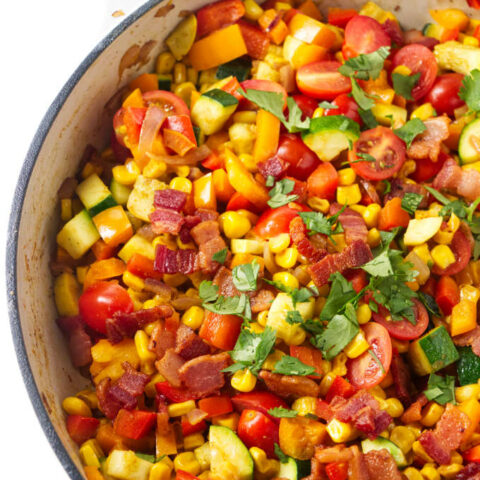 Corn succotash in a large skillet with bacon bits on top.