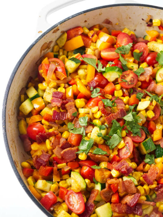 Corn succotash in a large skillet with bacon bits on top.
