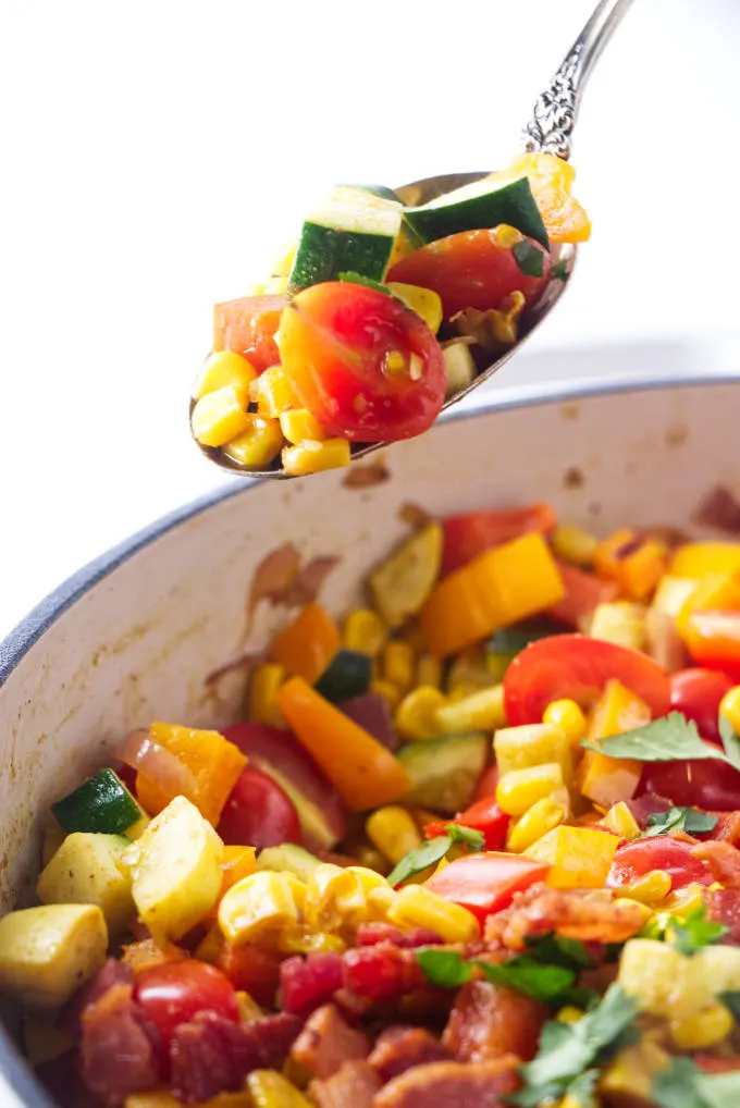 A spoon scooping our some corn succotash.