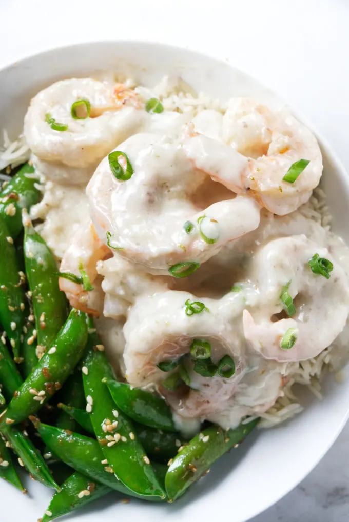 Creamy coconut shrimp on a serving of rice with some snow peas.