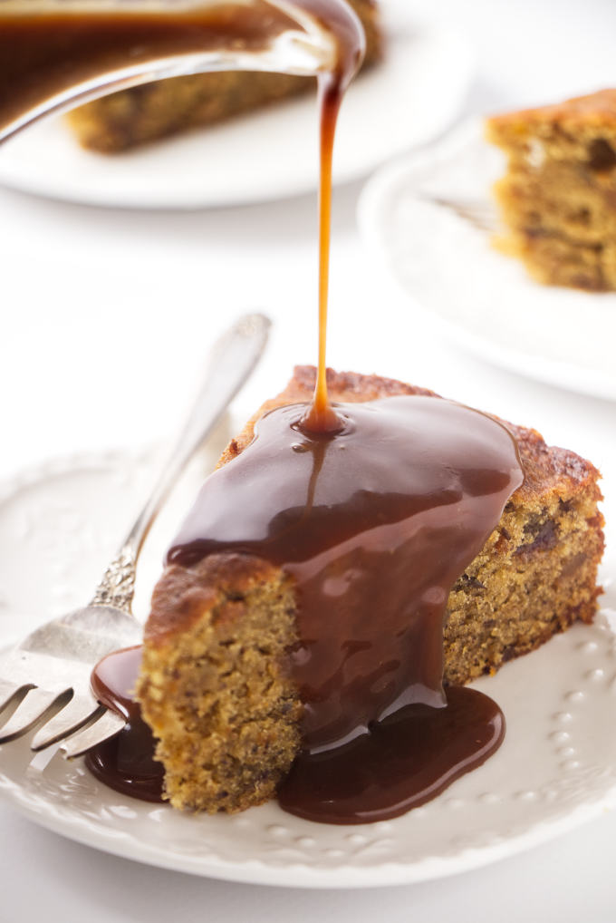 A slice of date cake with sticky toffee sauce being poured on top.