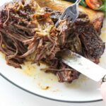 A beef rib being shred with a fork.