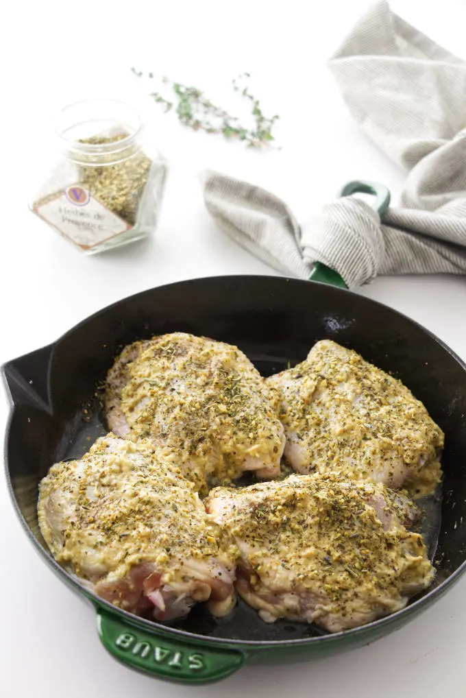 Four seasoned chicken thighs in a skillet ready to roast