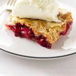 A slice of strawberry rhubarb slab pie with ice cream on top.