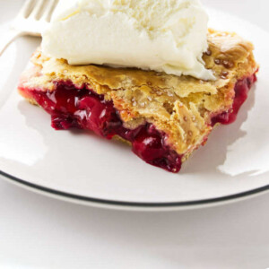 A slice of strawberry rhubarb slab pie with ice cream on top.