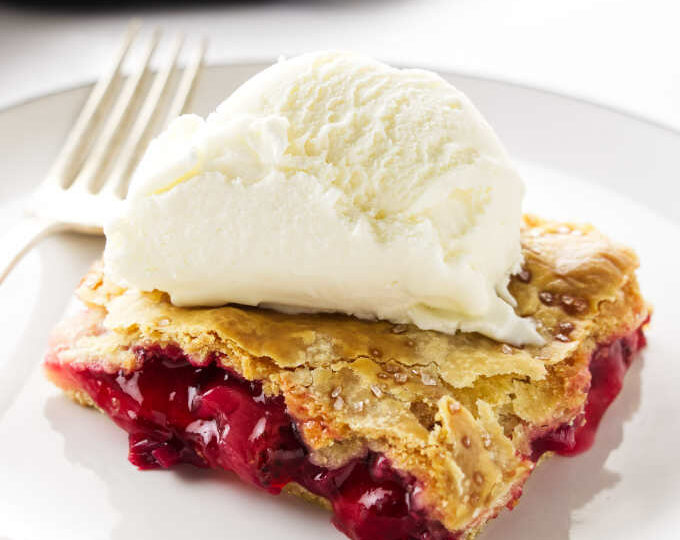 A serving of strawberry-rhubarb slab pie with a scoop of ice cream