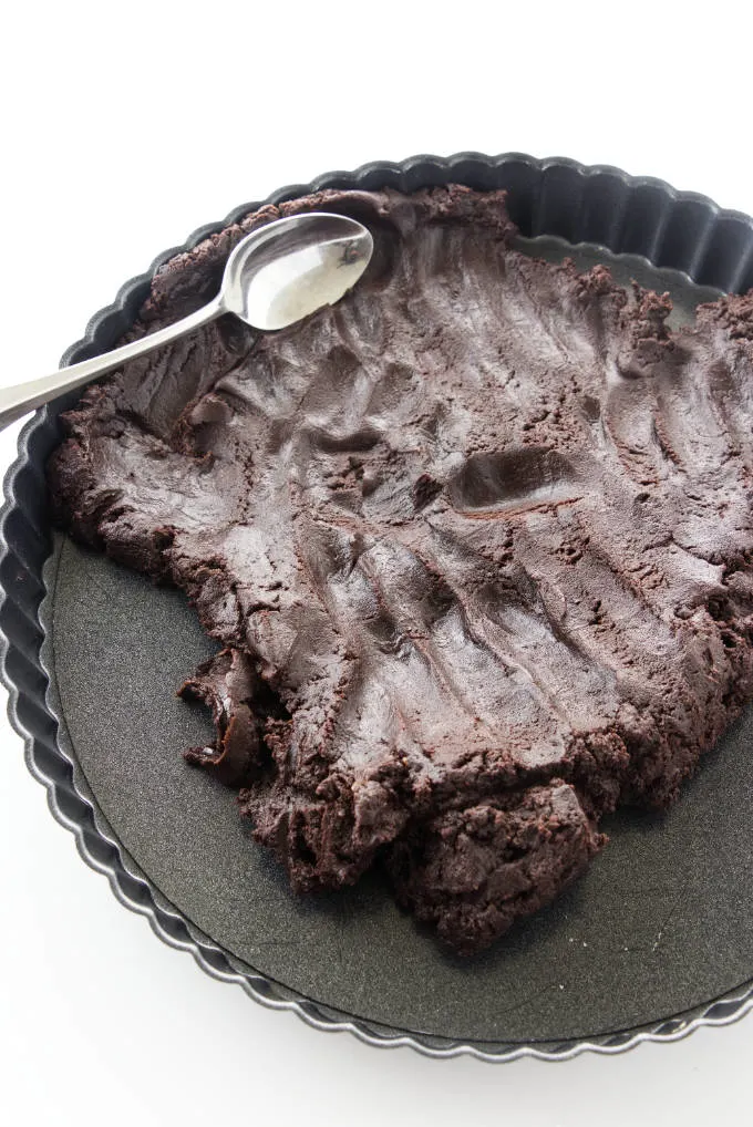 Pressing chocolate shortbread crust into a tart pan. 
