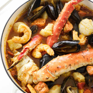 A large pot of seafood stew with king crab, shrimp, scallops, mussels, halibut, and salmon.