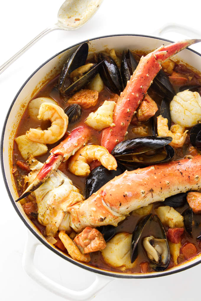 A large pot of seafood stew with king crab, shrimp, scallops, mussels, halibut, and salmon.