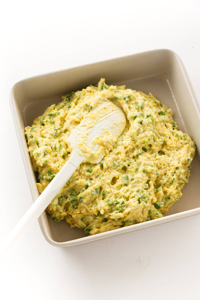 Spreading cornbread batter into a baking pan.