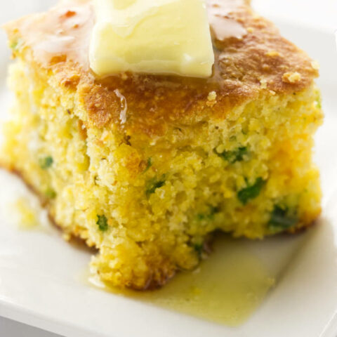 A slice of jalapeno cheddar cornbread with butter on top.