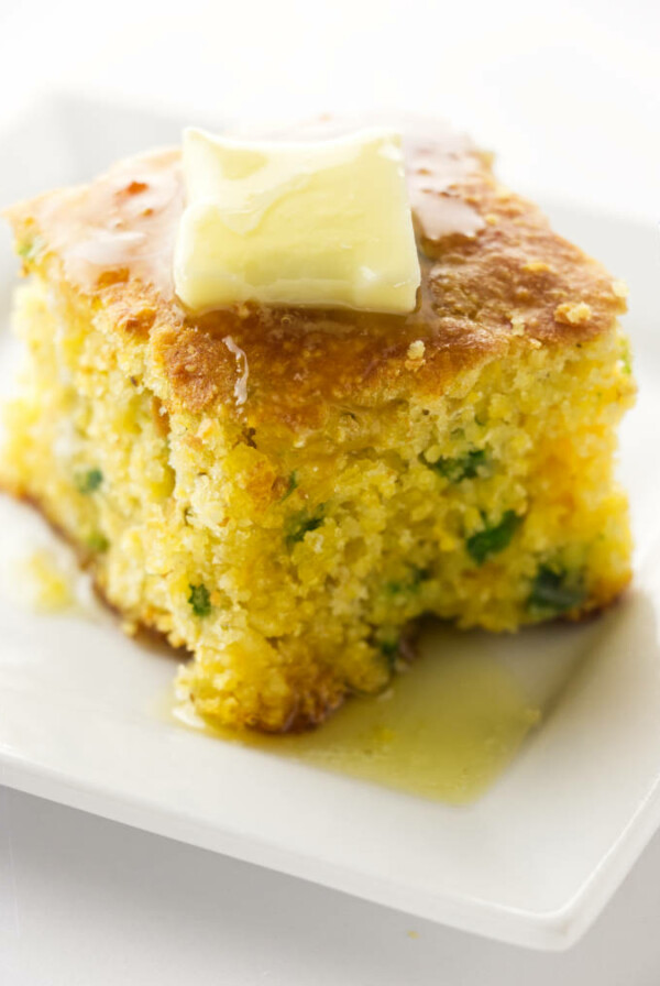 A slice of jalapeno cheddar cornbread with butter on top.