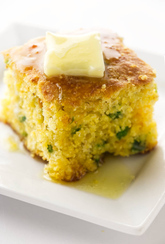 A slice of jalapeno cheddar cornbread with butter on top.