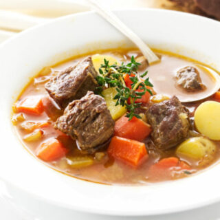 A bowl of lamb and vegetable soup with soup spoon