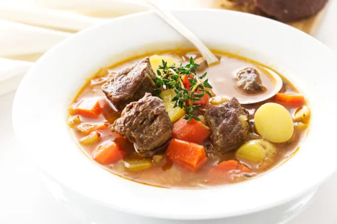 A bowl of lamb and vegetable soup with soup spoon