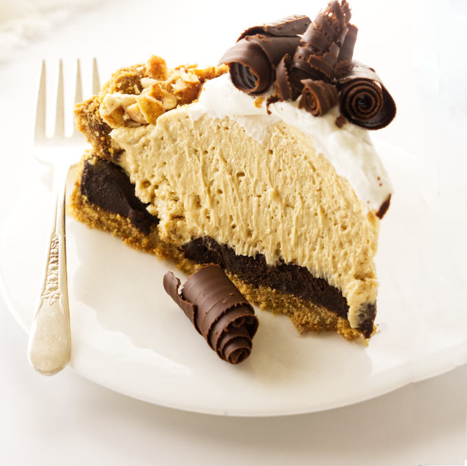 A slice of peanut butter pie with a chocolate bottom and graham cracker crust.