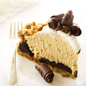 A slice of peanut butter pie with chocolate curls and graham cracker crust.