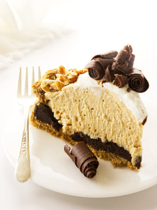 A slice of peanut butter pie with chocolate curls and graham cracker crust.