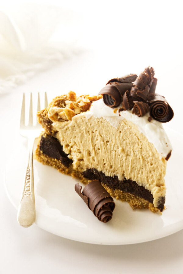 A slice of peanut butter pie with chocolate curls and graham cracker crust.