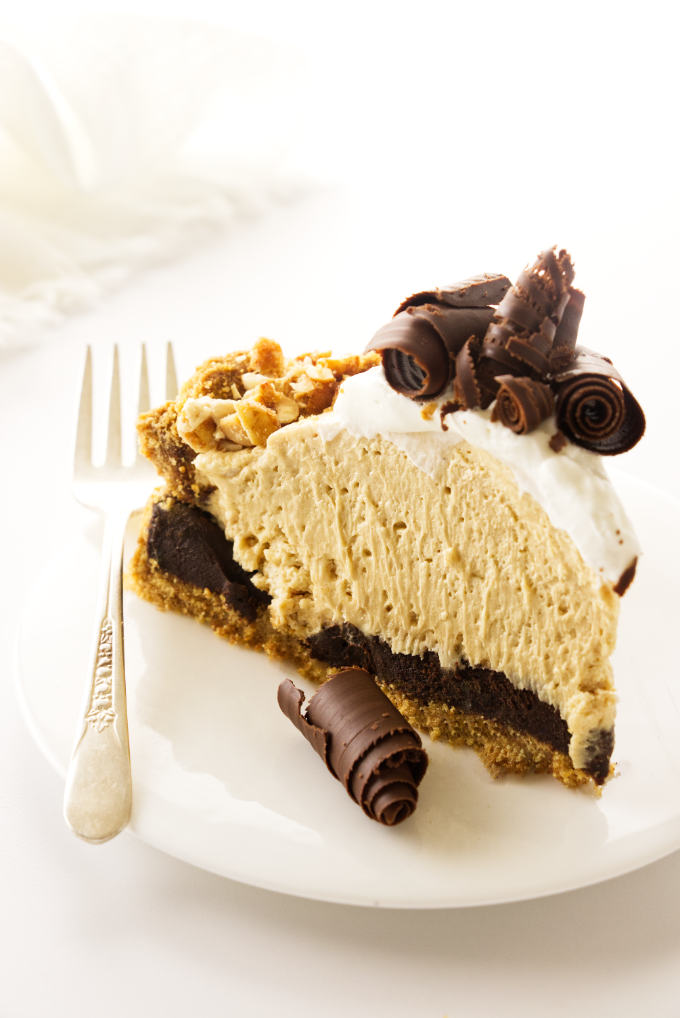 A slice of peanut butter pie with chocolate curls and graham cracker crust.