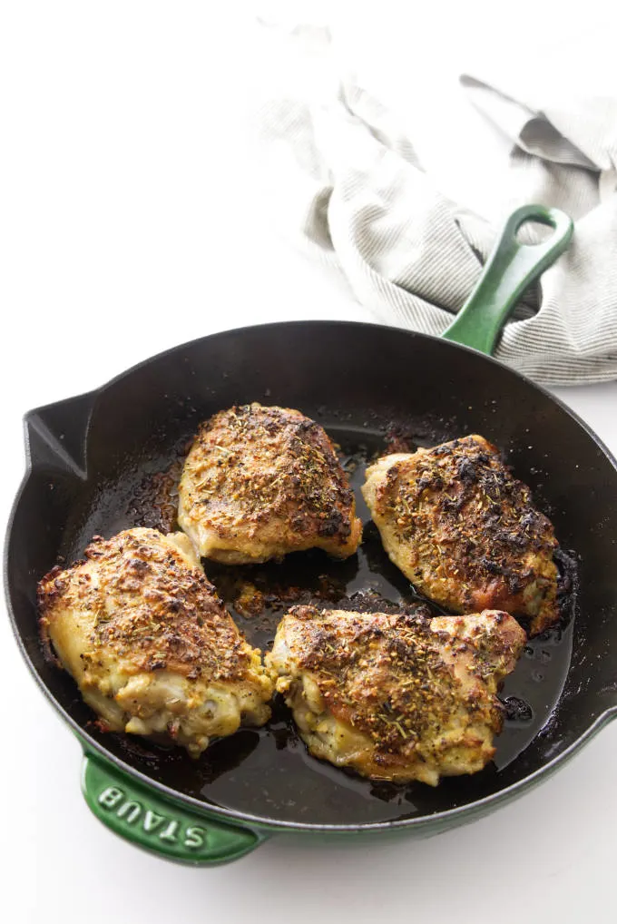 Four roasted chicken thighs in a skillet