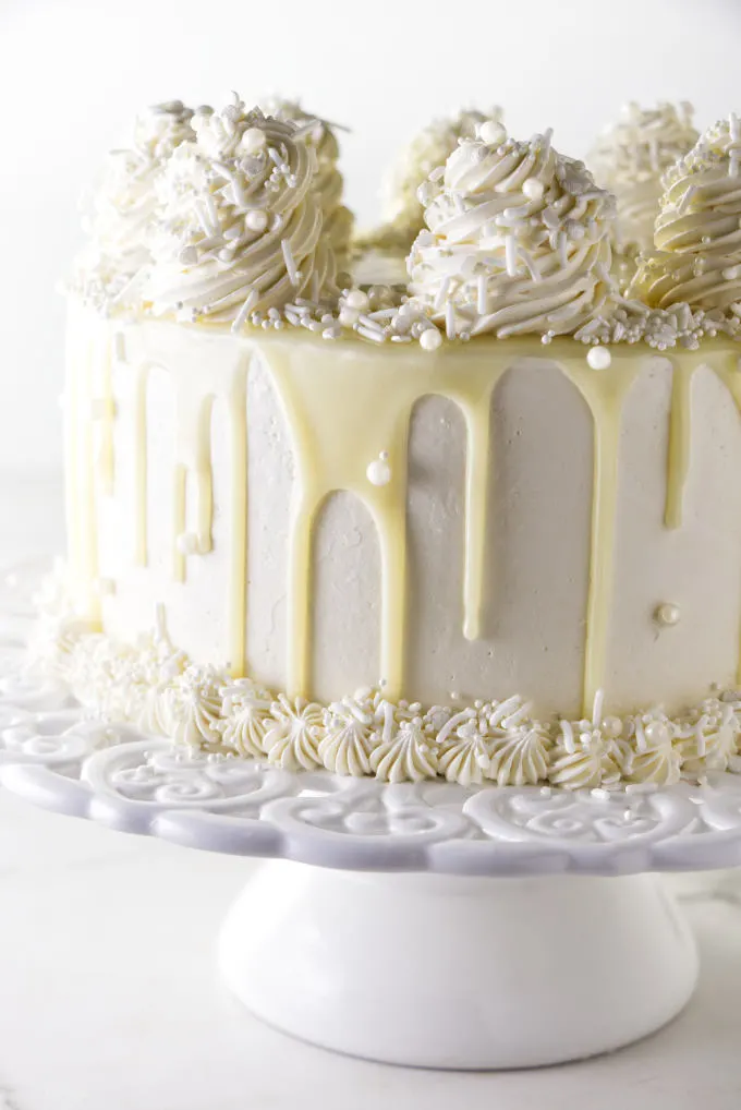 A white chocolate cake with white chocolate ganache dripping down the sides.
