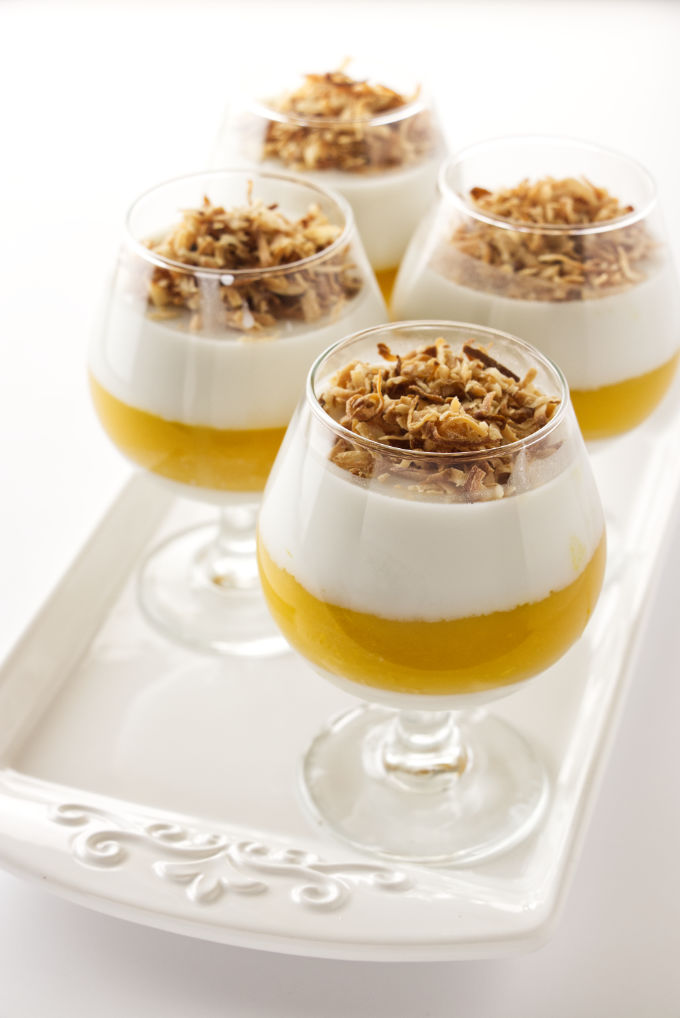 Four servings of coconut-mango panna cotta garnished with toasted coconut
