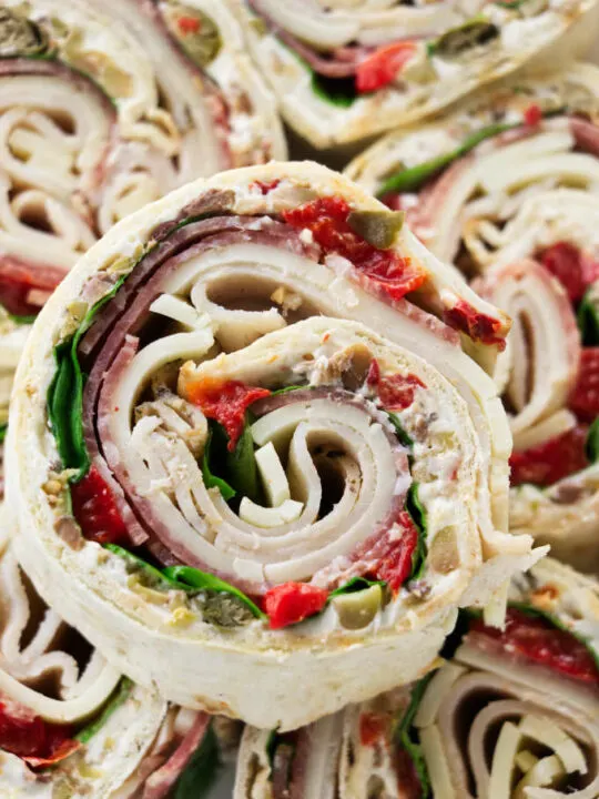 Italian pinwheel sandwich appetizers stacked on top of each other.