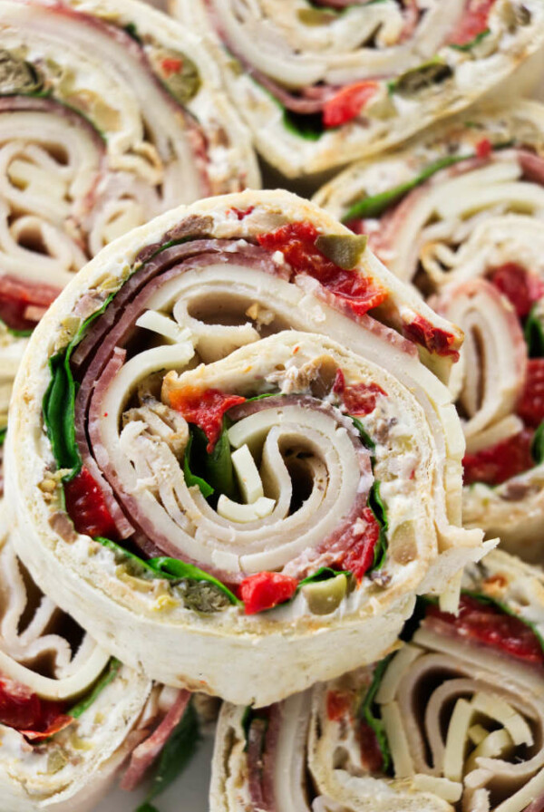 Italian pinwheel sandwich appetizers stacked on top of each other.