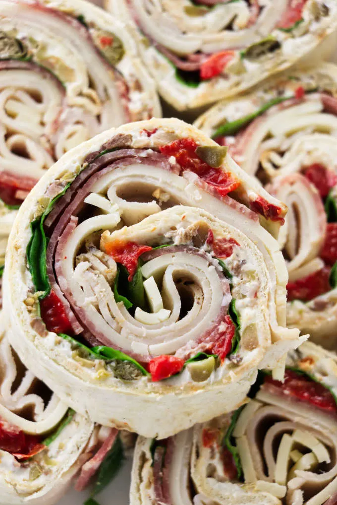 Italian pinwheel sandwich appetizers stacked on top of each other.